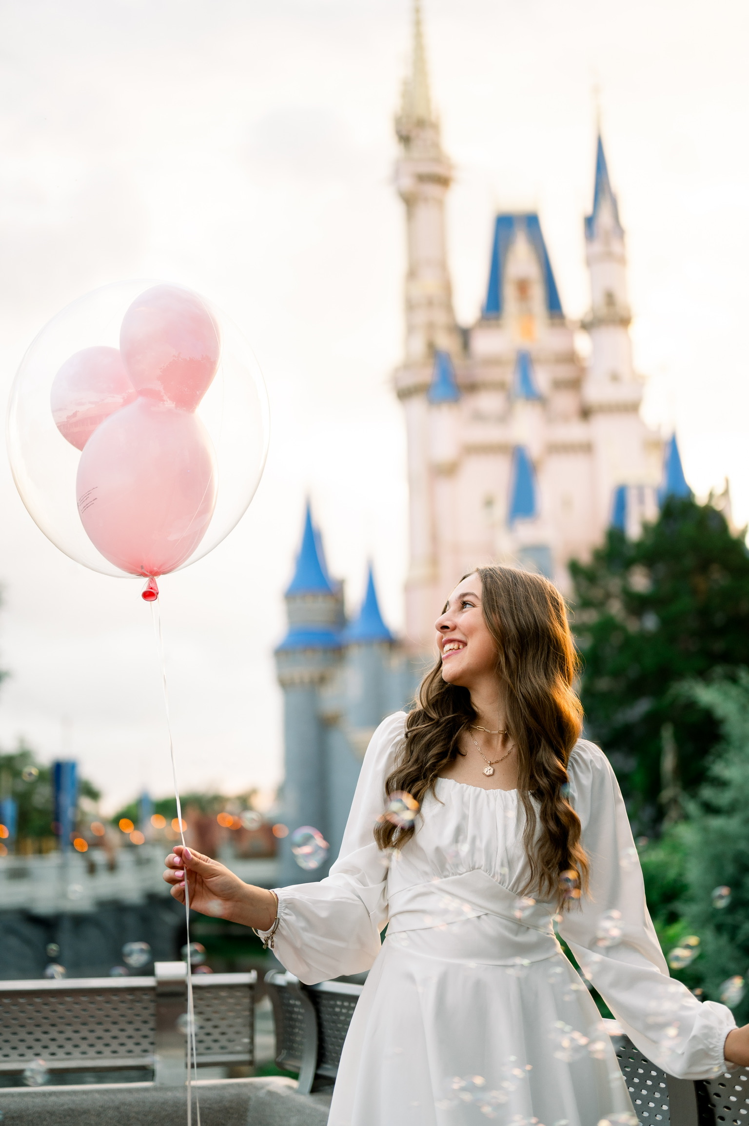 Kyree holding a pink Mickey balloon in front of Cinderella Castle