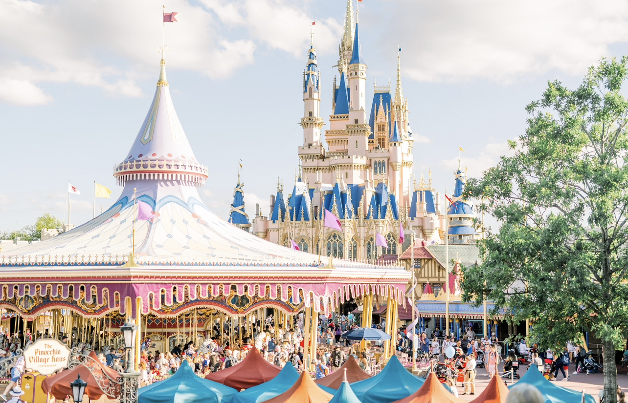Cinderella's Castle at Walt Disney World with colorful festival tents and crowds