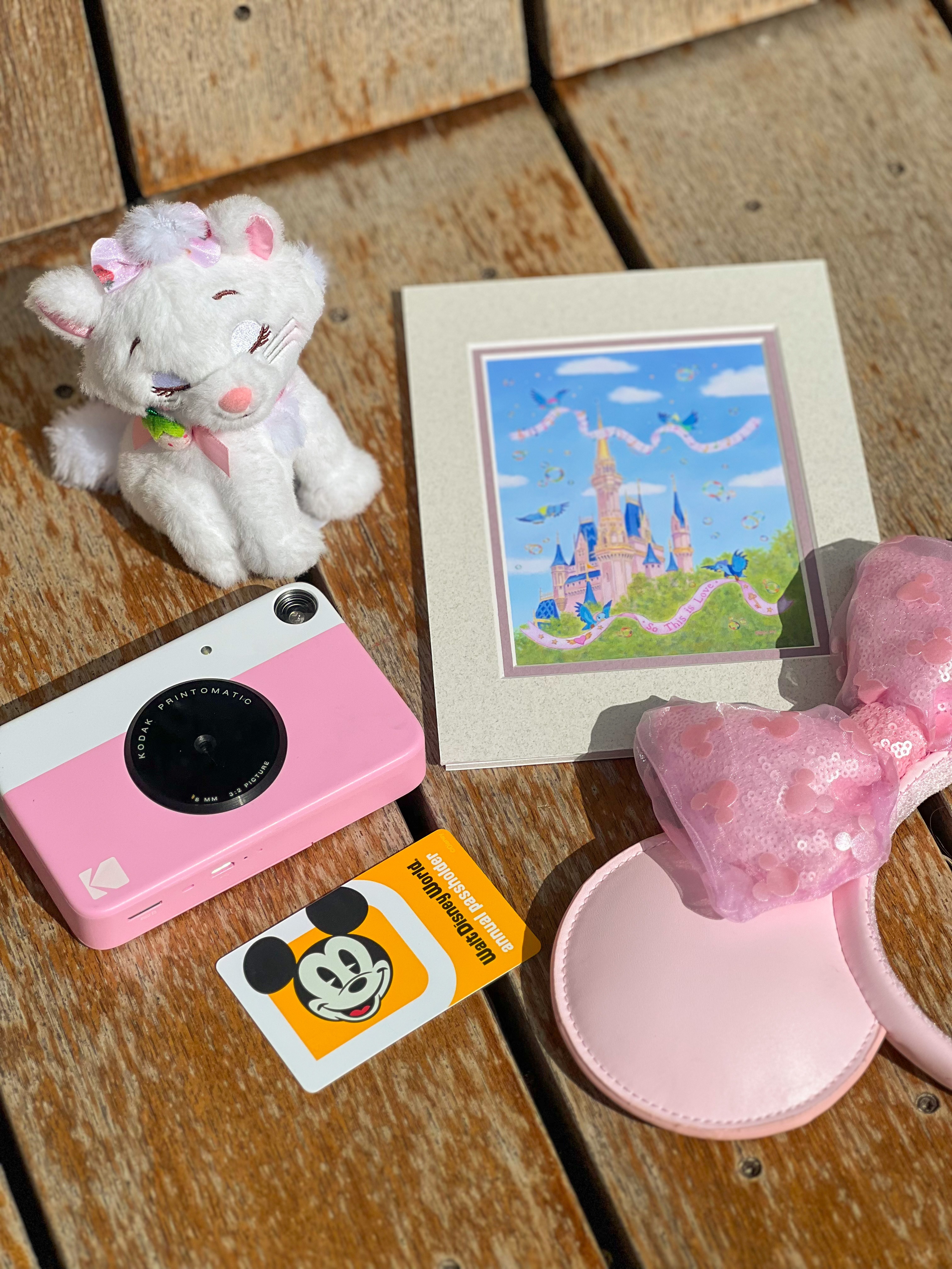 Disney collectibles and art arranged on a wooden surface